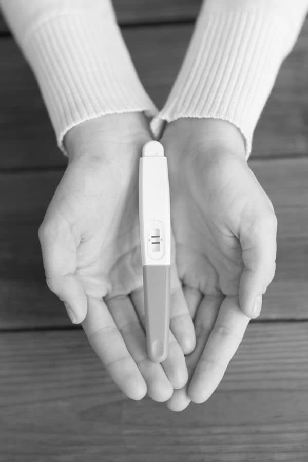 Woman's hands holding positive pregnancy test
